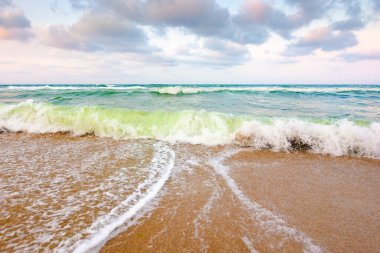 Deniz gelgitli doğa. Güzel sahil. Fırtına sırasında su yüzeyi hareketi. Islak sahilde köpüklü dalga sıçraması. Yazın rüzgârlı açık hava. Ufuk çizgili seyahat duvar kağıdının güzel manzarası