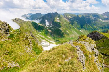 Yazın Romanya 'nın dağlık arazisi. Yüksek irtifa. Güneşli bir günde ibne dağ sırtı. Mavi gökyüzünün altında çimenli yamaçta karla kaplı manzaralı bir vadi. Tranylvania 'ya seyahat 