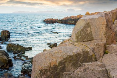 Sahildeki deniz taşları. kabataslak. Sahilde taşlarla birlikte doğayı gezmek. Deniz kenarında güzel bir yaz tatili. Mavi suyun sakin yüzeyi ve deniz manzaralı akşam gökyüzü