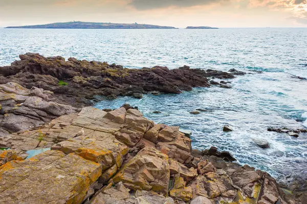 Sahildeki deniz taşları. Sahilde taşlarla birlikte doğayı gezmek. Dramatik ilham. Deniz kenarında güzel bir yaz tatili. Mavi suyun sakin yüzeyi ve deniz manzaralı akşam gökyüzü