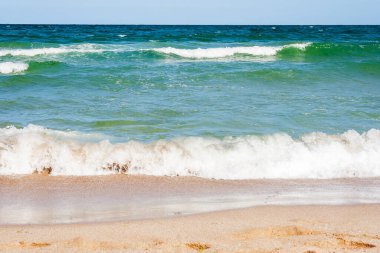 Yazın deniz manzarası. Altın kumu olan kumsal. Şeffaf sakin dalgalar ve mavi gökyüzü ile harika bir tatil geçmişi var. Kumlu deniz kıyısında macera