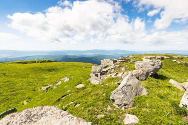 Güneşli bir sabahta alp çayır manzarası. Karpat Dağları 'nın yeşil tepelerindeki kayalar. Mavi gökyüzündeki bulutlar. açık hava macerası ve yürüyüş geçmişi