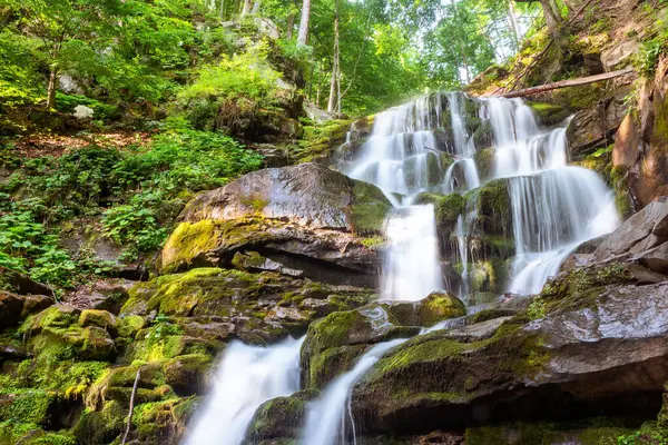 Yazın Karpat Dağları 'nın şelale çukuru. Ormanda ferahlatıcı bir rahatlama. Sabahın ilk ışıklarıyla manzara. Ukrayna 'nın popüler seyahat yeri. Ormandaki yosunlu kayaların üzerinde çağlayan kayalar.