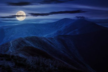 Geceleri dağ manzarası. Tepenin tepesinden dağın tepesine giden yol. Dolunay ışığında harika bir kır manzarası