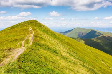 Yazın Carpathian sıradağları boyunca yol. Güneşli bir günde benekli ışıkta patikalı ve dik çimenli yamaçlı alp manzarası. Mavi gökyüzünde ufukta kabarık bulutlar