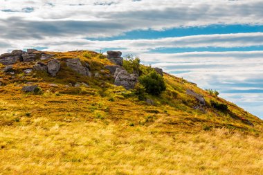 Yazın sonlarında güzel bir dağ manzarası. Turuncu çimenler arasındaki kaya oluşumunun manzarası. Gri bulutlu dramatik bir gökyüzü. Avrupa 'da tatil sezonu bitti