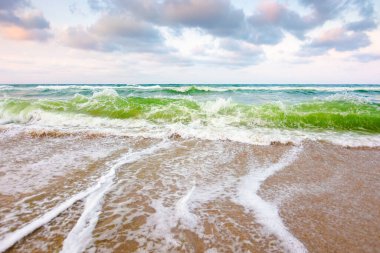 Akşam ışığında deniz gelgiti olan doğa arka planı. Fırtına sırasında su yüzeyi hareketi. Islak sahilde köpüklü dalga sıçraması. Yazın rüzgârlı açık hava. Ufuk çizgili seyahat duvar kağıdının güzel manzarası