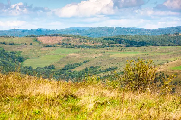 Sonbahar öğleden sonra erken saatlerde dağlık kırsal alan. Saha manzarası ve yuvarlanan tepelerde çayırlar. Gökyüzünde bulutlarla güneşli bir gün