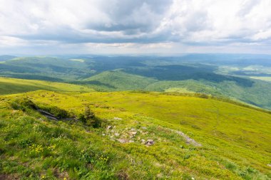 Dağın tepesinden vadiye güzel bir manzara. Yeşil tepeler ve çayırlar. Karpatlar 'ın menzilinden geçeceğiz. Yazın güneşli hava Bulutlu gökyüzü