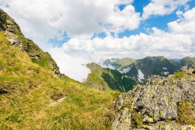 Yazın Romanya 'nın dağlık arazisi. Kayalık bir manzara. Güneşli bir günde ibne dağ sırtı. Mavi gökyüzünün altında çimenli yamaçta karla kaplı manzaralı bir vadi. Tranylvania 'ya seyahat