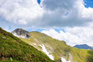 Romanya 'nın dağlık arazisi bulutlu gökyüzü altında. Yaz tatili sezonunda yürüyüş için Avrupa manzarası seyahat arka planı. Transilvanya Alplerindeki dik kayalık yamaçlı ibnelerin manzarası