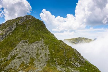 Romanya 'nın dağlık arazisi bulutlu gökyüzü altında. Yaz tatili sezonunda yürüyüş için Avrupa manzarası seyahat arka planı. Transilvanya Alplerindeki dik kayalık yamaçlı ibnelerin manzarası