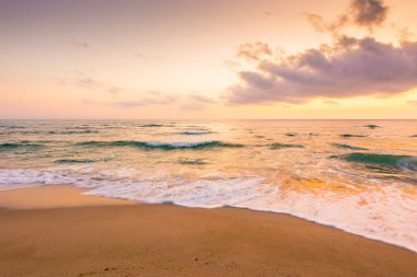 Denizde yaz tatili. Sakin bir sıçrama. Güneşin doğuşunda güzel pembe deniz manzarası. Sakin dalgalar altın kumlu sahili yıkıyor. Gökyüzünde kabarık bulutlar. Turizm cenneti