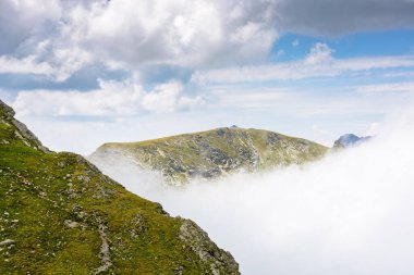 Romanya 'nın dağlık arazisi bulutlu gökyüzü altında. Yaz tatili sezonunda yürüyüş için Avrupa manzarası seyahat arka planı. Transilvanya Alplerindeki dik kayalık yamaçlı ibnelerin manzarası
