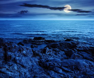 Yazın geceleri kayayla kaplı deniz manzarası. Taş sahili ve dolunay ışığında dalgalanan güzel bir manzara. İspanya 'da gizemli bir sahne