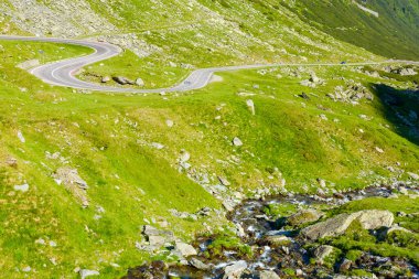 Yazın transfagarasan yolu ile manzara. Romanya seyahati. Güneşli bir sabahta dik kayalık tepeleri ve su akıntısı olan vadinin manzarası. Tranylvania 'nın alp manzarası