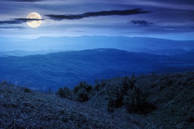 Yazın geceleri dağ manzarası. Dolunay ışığında yeşil tepelerin ve alp çayırlarının güzel manzarası. Karanlık gökyüzünde bulutlu manzara. seyahat için doğal ortam arka planı