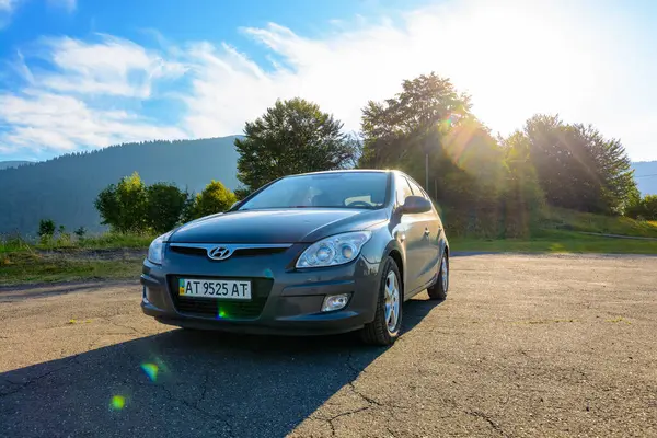 Mizhhirya, Ukrayna - 08 Ağustos 2020: dağ manzarasında kare asfalt kaldırımda araba. Yaz seyahatleri için doğa geçmişi. Güneş mavi gökyüzünde. arka aydınlatma küçük araç