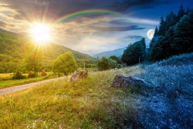 Yazın bulutlu gökyüzü olan kırsal alan. Gündüz ve gece zaman kavramını değiştirir. Alacakaranlıkta güneş ve ay olan çimenli tepede bir orman. Bulutlu hava tahmini. Dağdaki uzak kırsal manzara