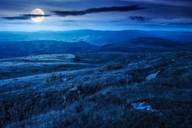 Yazın geceleri dağ manzarası. Dolunay ışığında yeşil tepelerin ve alp çayırlarının güzel manzarası. Karanlık gökyüzünde bulutlu manzara. seyahat için doğal ortam arka planı