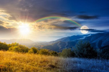 Sonbahar ekinoksu sırasında tepesinde orman olan dağ manzarası. Gündüz ve gece zaman kavramını değiştirir. Kırsal vadiye güzel bir manzara. Alacakaranlıkta güneş ve ayın olduğu dağlık arazi manzarası