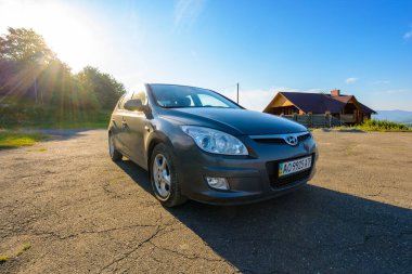 Mizhhirya, Ukrayna - 08 Ağustos 2020: dağ manzarasında kare asfalt kaldırımda araba. Yaz seyahatleri için doğa geçmişi. Güneş mavi gökyüzünde. arka aydınlatma küçük araç