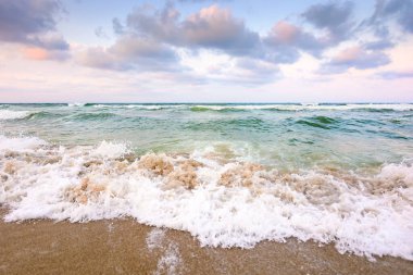 Fırtınadan önce deniz gelgiti. Islak kumsalda köpüklü dalgalar. Kadife mevsiminde rüzgarlı bir hava. dramatik deniz manzarası arkaplanı