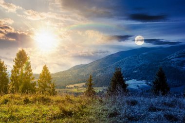 Dağ sırasının yamacında kozalaklı orman ve çayır var. Gündüz ve gece zaman kavramını değiştirir. Eylül 'de, güneş ve ayın alacakaranlıkta olduğu Karpat Dağı manzarası.