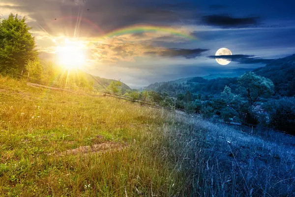 Yazın bulutlu gökyüzü olan kırsal alan. Gündüz ve gece zaman kavramını değiştirir. Alacakaranlıkta güneş ve ay olan çimenli tepede bir orman. Bulutlu hava tahmini. Dağdaki uzak kırsal manzara