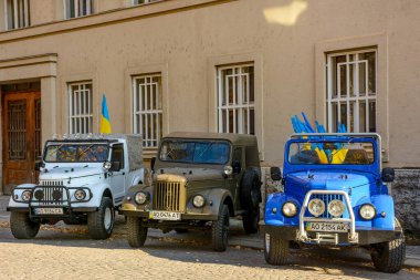 Uzhhorod, Ukrayna - 31 Ekim 2021: 3 off-road-ready old-timer cars. Asfalt yolda Ukrayna bayraklı arabalar. Eski askeri ulaşım turizm ve eğlence için modifiye edildi ve ayarlandı