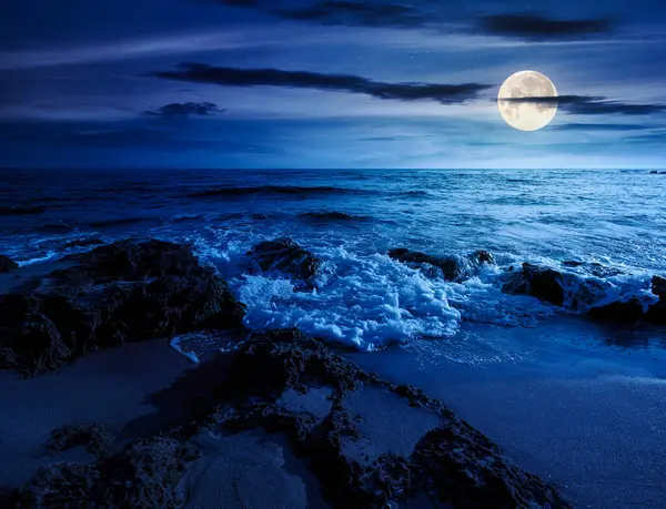 Kumsalda geceleri kum olur. Yaz tatilinde deniz kenarında. Dolunay ışığında sakin dalgalarla güzel bir deniz manzarası. Gökyüzünün altında kabarık bulutlarla deniz manzarası