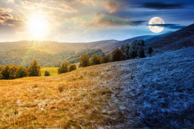 Dağlarda sakin bir sonbahar günü. Gündüz ve gece zaman kavramını değiştirir. Tepenin çimenli tepelerinde yaprak döken ağaçlar. Sonbahar mevsiminde, güneş ve ayın altında alp manzarası. Doğadaki güzellik kavramı
