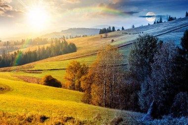 Sonbahar ekinoksunda çimenli tepede bir orman. Gündüz ve gece zaman kavramını değiştirir. Yuvarlanan otlaklı güzel kırsal manzara. Alacakaranlıkta güneş ve ayın olduğu dağlık bir kırsal. Sıcak Ekim havası