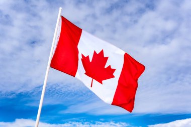 National flag of Canada flowing in wind with blue sky background.
