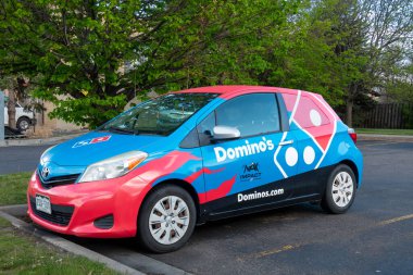 FORT COLLINS, CO, USA - MAY 13, 2024: Domino's Pizza delivery vehicle and trademark logo. clipart