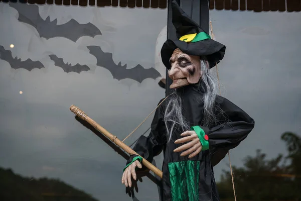 Witch doll decoration with broom and many flying bats. Halloween decor concept.