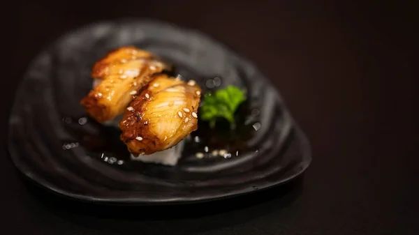 暗めの背景にテキストのためのコピースペースと黒料理のアナゴうなぎ寿司 — ストック写真