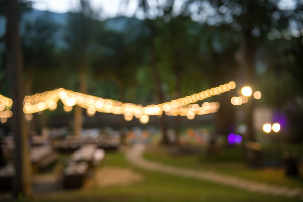 Blur image of outdoor garden restaurant with light decoration by river in Kanchanaburi, Thailand.