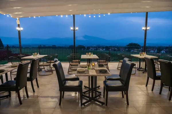 Romantic dinner tables by patio with beautiful mountain and valley view with mist at dusk. Beautiful view in holiday vacation.