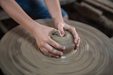 Closeup kid hands make clay pot to jar or vase in Koh Kret, Nonthaburi, Thailand.