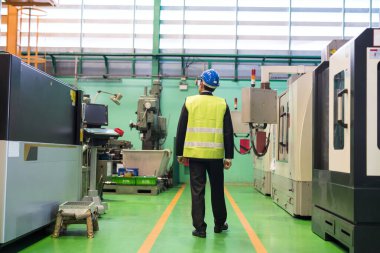 Rear of businessman or factory manager with hardhat walk along production department to inspect microchip semiconductor machine. Industry business.