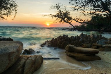motion wave seascape through stone arch at sunrise in Ko Man Klang, Rayong, Thailand. Famous travel destination and summer holiday vacation in tropical country, Siam.