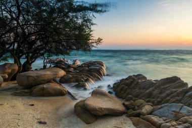 Ko Man Klang, Rayong, Tayland 'da gün doğumunda sahildeki taştan deniz manzarası. Ünlü tatil beldesi ve yaz tatili, tropikal ülke Siyam 'da.