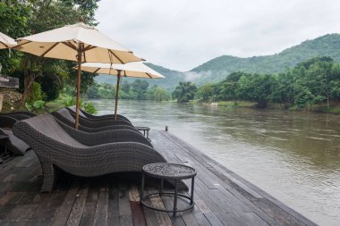 Sabah Kwai nehrinin kıyısındaki ahşap iskelede güneşli yatak koltukları ve Kanchanaburi, Tayland 'da sis..