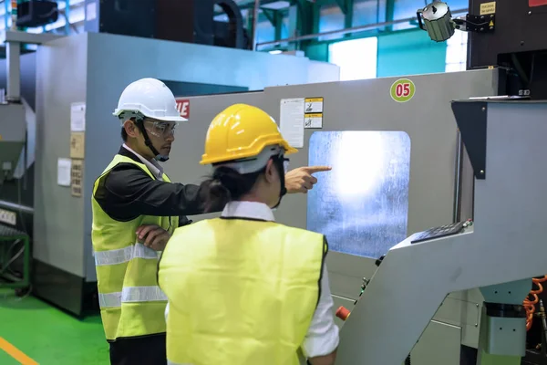 Factory audit manager point finger to screen while female inspector note on paper to examine microchip machine. Manufacturing industry with CNC lathe automated machines. Quality assurance