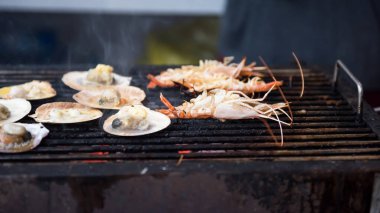 Izgara deniz tarağı ve tavada sıcak dumanlı deniz karidesi. Akşamki aile partisi için barbekü veya bbq