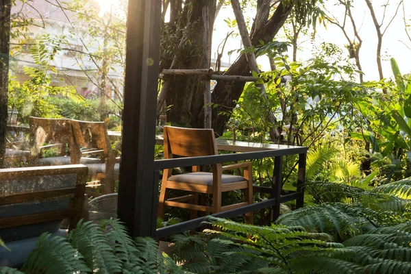 咖啡店的木制椅子和庭院里的桌子 在日落时与春天的花园一起畅饮 在有自然环境的扶手椅上饮酒 — 图库照片
