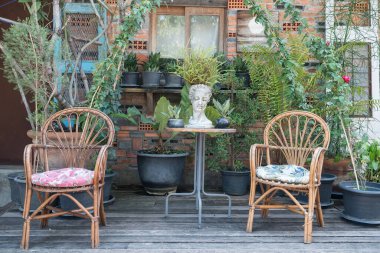 Tahta sandalyeler ve Koh Kret, Nonthaburi, Tayland 'daki kafede bitki süslemeli masa..