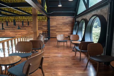 Ahşap koltuklar ve ikinci kattaki masa. Açık hava manzaralı. Kahve dükkanının camları yuvarlak. Lüks iç mimari tasarımı.