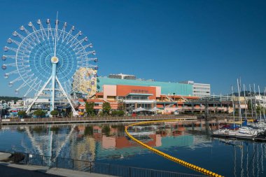 Shizuoka, Japonya - 27 Nisan 2023: S-Pulse Dream Plaza ve Shimizu 'daki mavi gökyüzüne karşı ufuk çizgisi yansıması olan feribot tekerleği. Maruko çizgi film temalı parkı olan ünlü alışveriş merkezi..